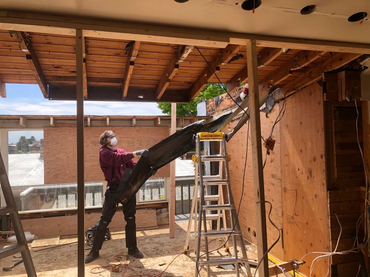 Worker sending debris down a chute from a second-floor window